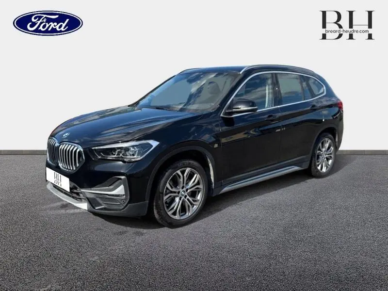 BMW X1 xDrive25eA 220ch xLine 2021 en Saphirschwarz vue 3/4 avant droit avec jantes alu et calandre chromée.