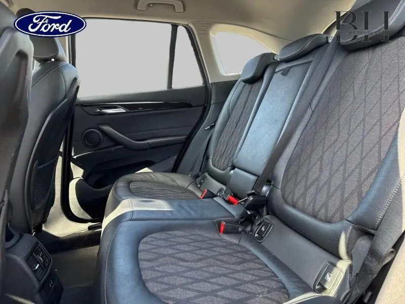 Vue intérieure côté droit des sièges arrière en cuir noir et tissu à motifs d'un BMW X1 xDrive25eA 2021.