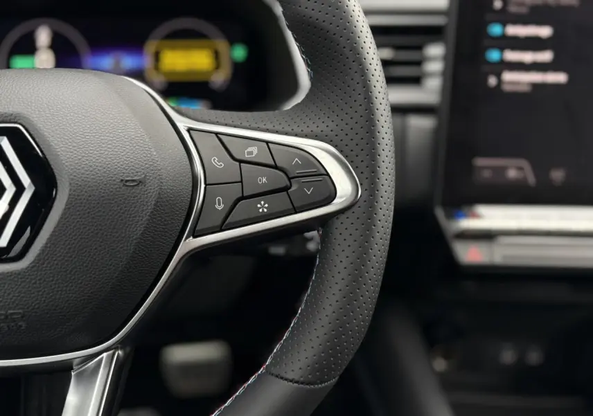 Gros plan sur le volant perforé noir avec surpiqûres bleu blanc rouge du Renault Captur Esprit Alpine 2025.