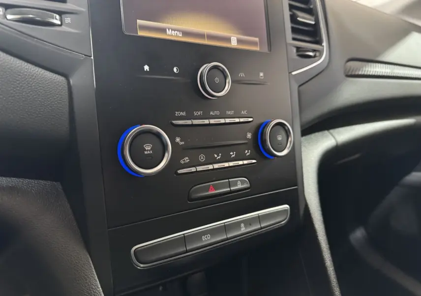 Vue rapprochée de la console centrale noire de la Renault Mégane Business avec commandes climatisation et écran tactile.