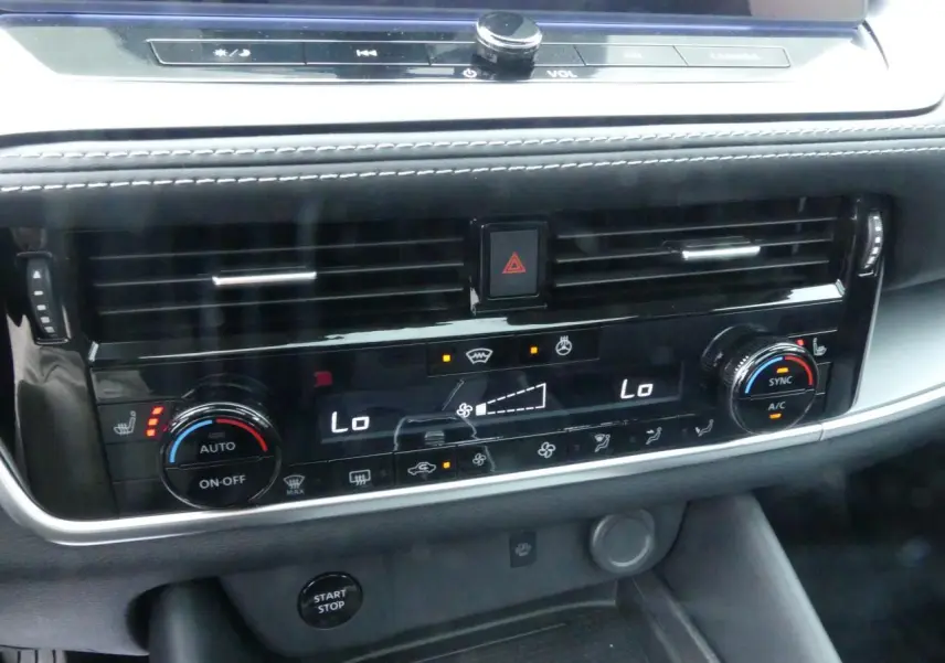 Tableau de bord du Nissan Qashqai 1.5 e-Power 2025, avec commandes climatisation bi-zone et bouton Start/Stop visibles.