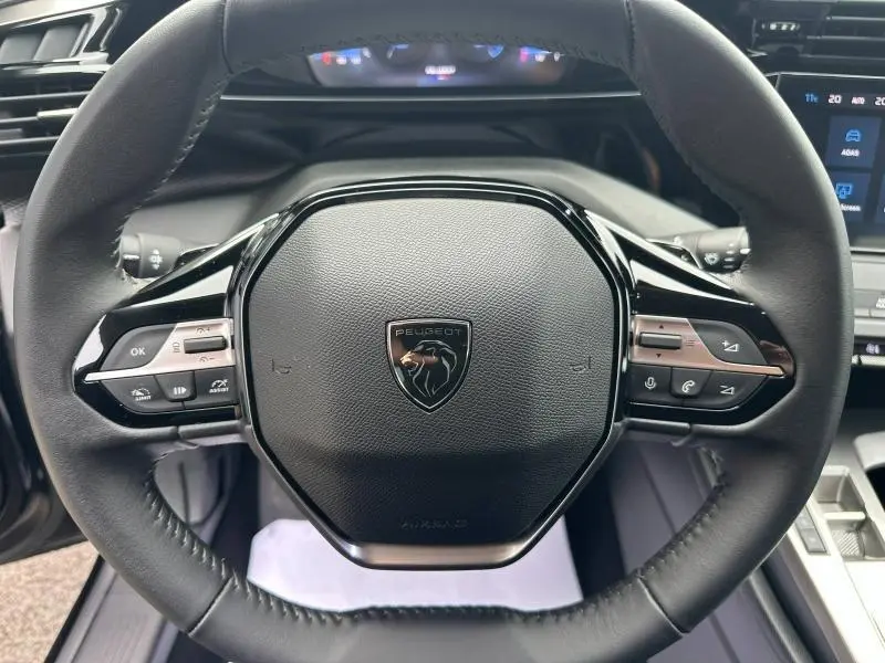 Vue rapprochée du volant noir de la Peugeot 308 2024 avec commandes intégrées et logo lion central.