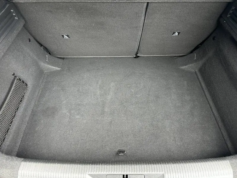 Coffre vide vu de dessus du Peugeot 308 2024 en Noir Perla Nera, avec revêtement tissu gris foncé et filet latéral.