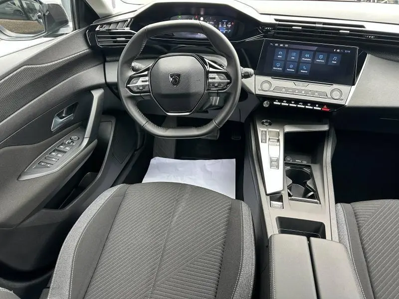 Vue intérieure avant de la Peugeot 308 2024 noir Perla Nera, avec volant compact, écran tactile et console centrale moderne.
