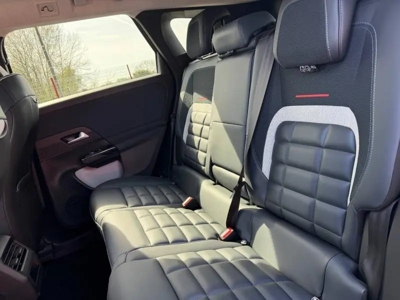 Vue intérieure des sièges arrière en cuir noir et tissu bleu du Citroën C5 Aircross 2026, avec accoudoir central rabattable.