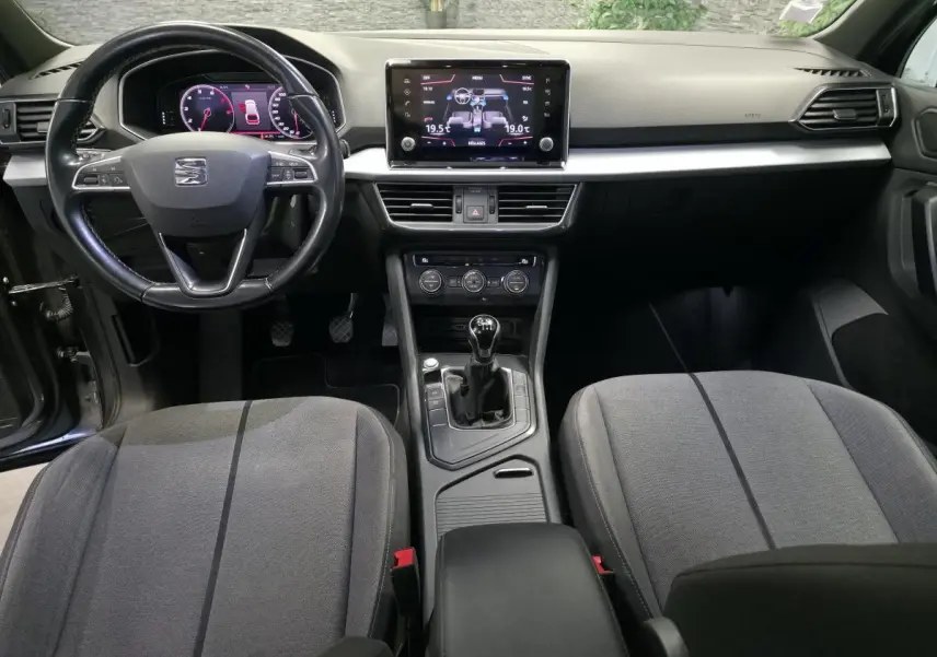 Vue intérieure avant du SEAT Tarraco gris, montrant le tableau de bord, volant cuir multifonction et levier de vitesse manuel.