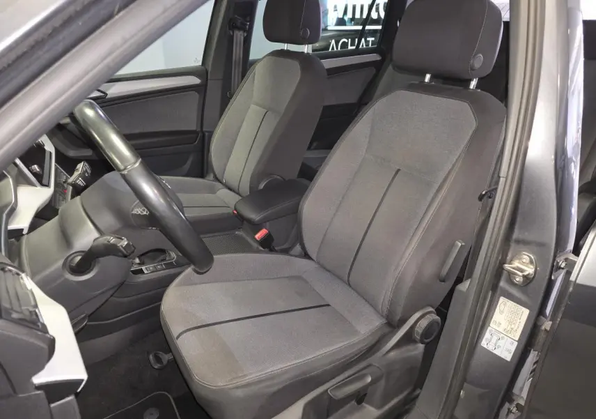 Vue intérieure côté conducteur du SEAT Tarraco gris, mettant en valeur les sièges tissu gris et le volant cuir multifonction.