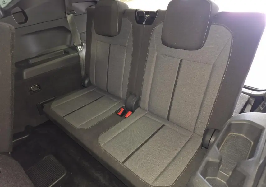 Vue intérieure du troisième rang de sièges tissu gris du SEAT Tarraco 1.5 TSI 7 places, avec ceintures et appuie-têtes.