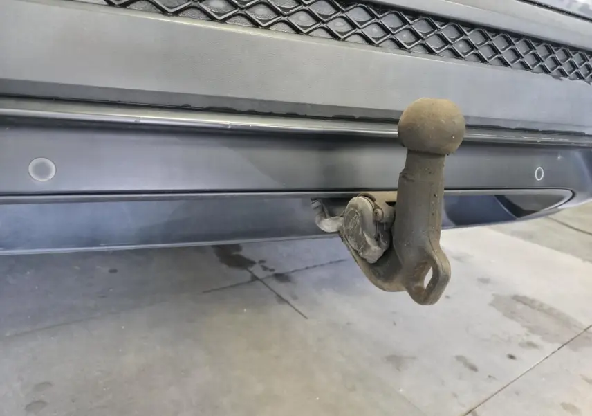 Gros plan sur le crochet d'attelage escamotable arrière du SEAT Tarraco gris, avec capteurs de stationnement visibles.