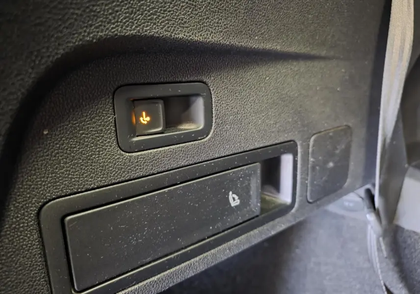 Détail du bouton de rabattement électrique des sièges arrière sur le côté droit d’un SEAT Tarraco gris.