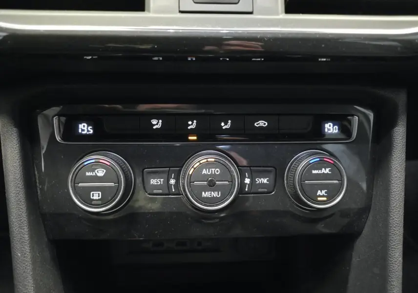 Gros plan sur la console centrale noire du SEAT Tarraco 2020, montrant les commandes de climatisation tri-zone digitales.
