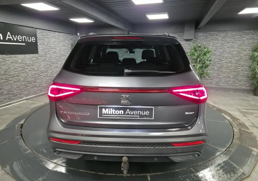 Vue arrière d'un SEAT Tarraco gris avec feux LED allumés et crochet d'attelage escamotable visible.