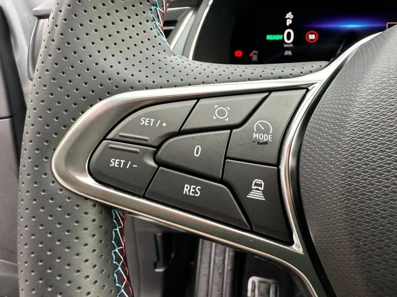 Gros plan sur les commandes au volant côté gauche du Renault Captur 2026 gris Rafale/Noir Étoilé avec surpiqûres tricolores.