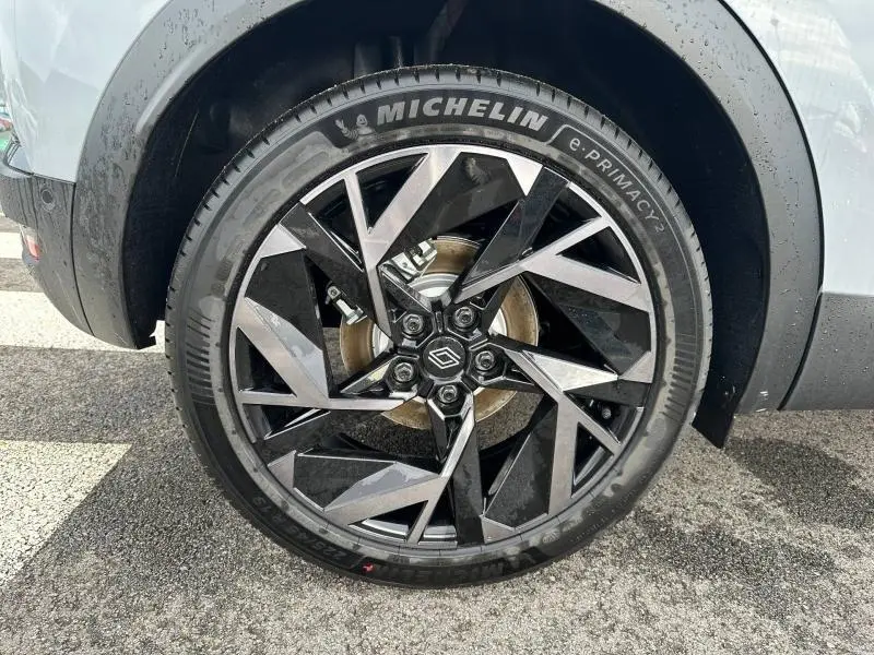 Gros plan sur la roue avant gauche du Renault Captur 2026 gris Rafale/Noir Étoilé avec jante noire et argentée au design géométrique.