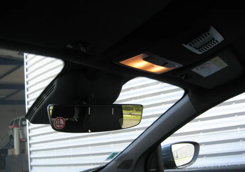 Vue intérieure côté conducteur du rétroviseur et du plafonnier allumé d'une MG3 1.5 Hybrid gris 2025.