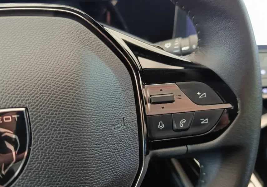 Gros plan sur le volant cuir noir multifonctions de la Peugeot 308 2023 avec commandes vocales et audio intégrées.