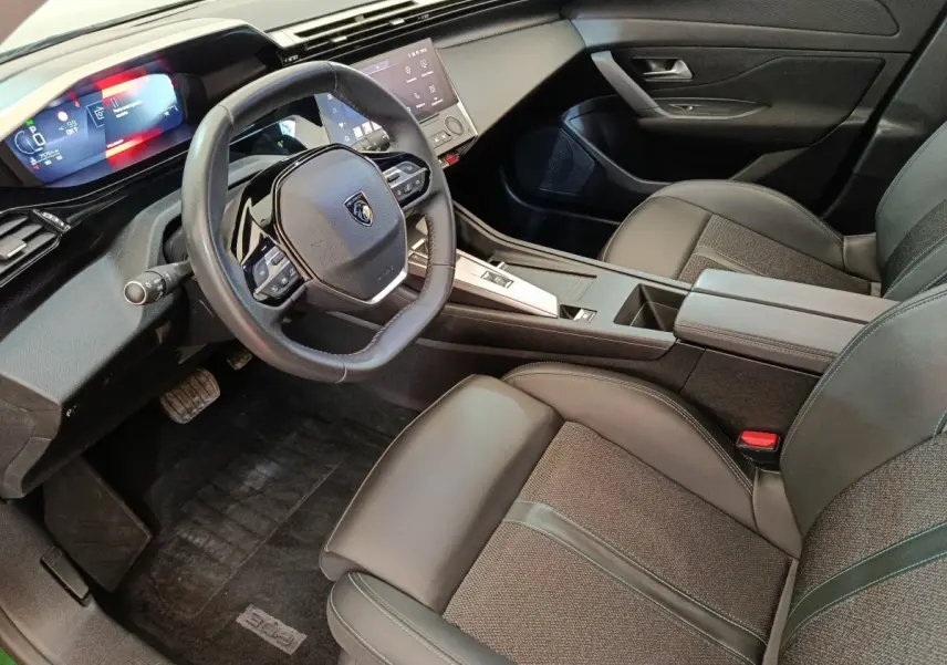Vue intérieure côté conducteur de la Peugeot 308 2023, volant cuir multifonctions et tableau de bord digital.