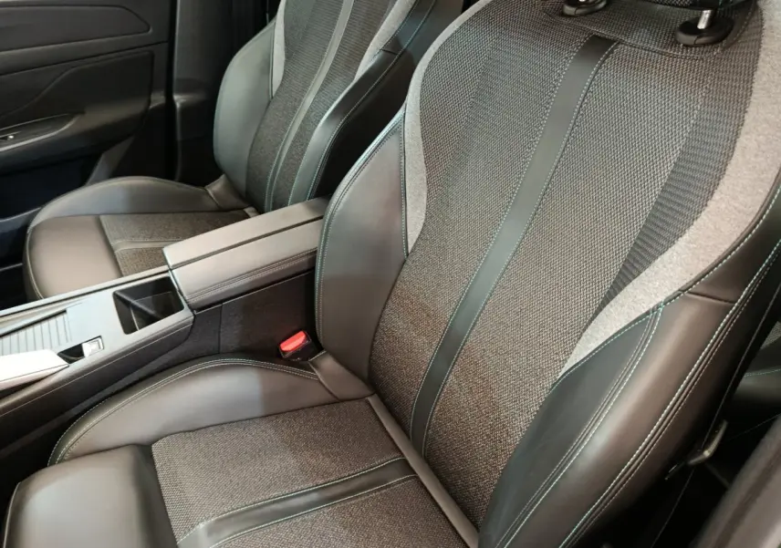 Gros plan sur les sièges avant en cuir et tissu gris avec surpiqûres vertes de la Peugeot 308 2023.