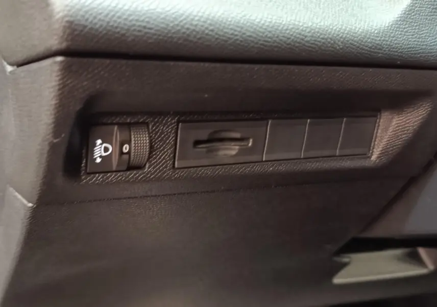 Vue rapprochée du tableau de bord noir de la Peugeot 308 2023, avec commande de réglage des phares.