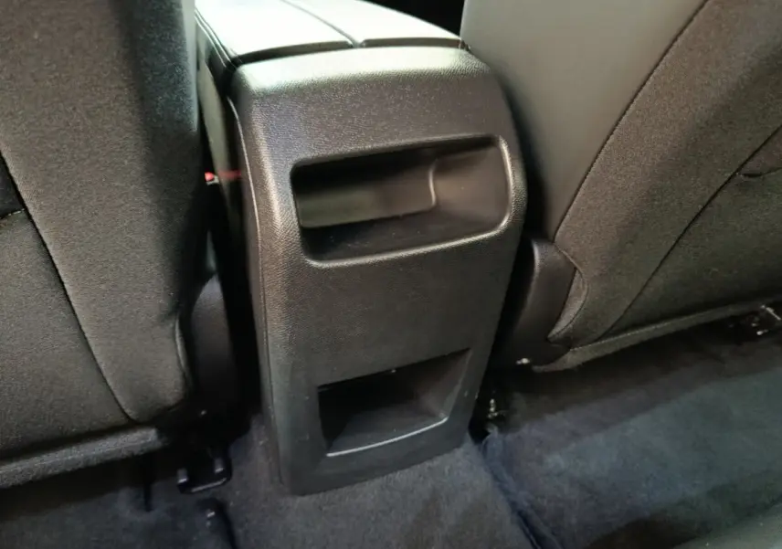 Vue rapprochée de la console centrale arrière noire entre les sièges arrière d'une Peugeot 308 2023.