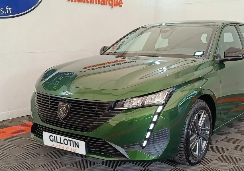 Vue 3/4 avant d'une Peugeot 308 2023 vert métallisé avec feux LED verticaux et calandre noire distinctive.