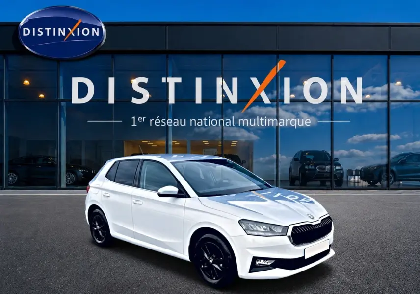 Vue 3/4 avant droite d'une Skoda Fabia blanche 2025 avec jantes noires devant un showroom Distinxion.
