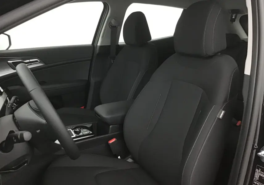 Vue intérieure du côté conducteur du Kia Sportage noir 2025, mettant en valeur les sièges avant en tissu avec coutures contrastées.