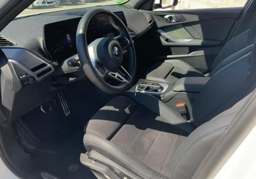 Intérieur avant droit de BMW Série 1 118D blanc, sellerie Alcantara noire et volant M cuir multifonctions.