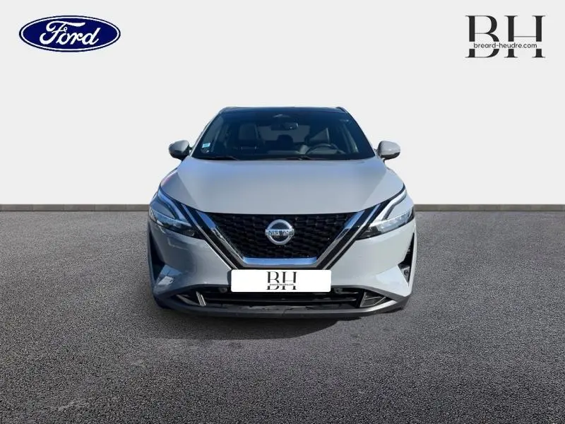 Vue de face du Nissan Qashqai 1.3 Mild Hybrid 140ch Tekna en gris Argile avec calandre noire et phares LED fins.