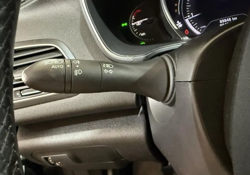 Gros plan sur la commande des phares et clignotants à gauche du volant dans l’habitacle noir de la Renault Mégane 2019.