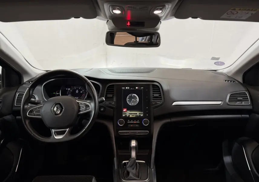 Vue intérieure frontale du tableau de bord de la Renault Mégane Intens 2019 avec écran tactile vertical et volant cuir noir.