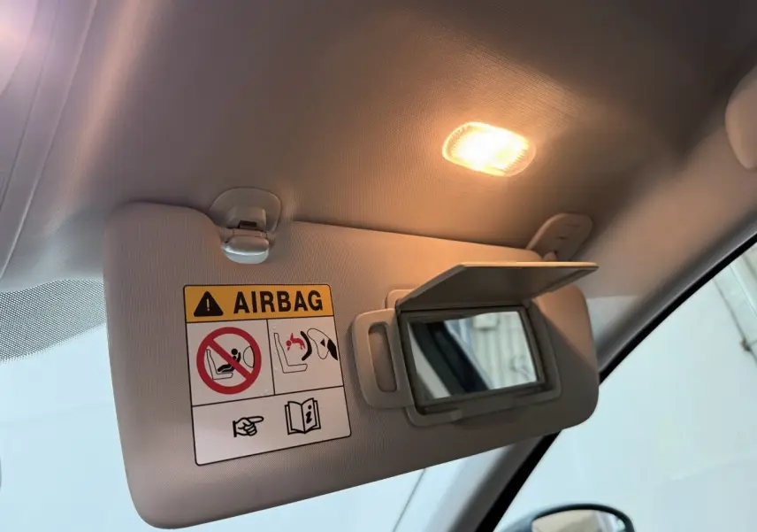 Détail du pare-soleil côté conducteur avec miroir ouvert et lumière intérieure allumée dans une Renault Mégane gris foncé.