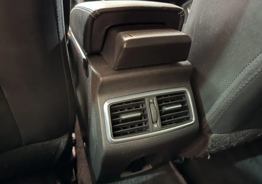 Détail des aérateurs arrière noirs avec réglage central, entre les sièges avant d'une Renault Mégane Intens gris foncé.