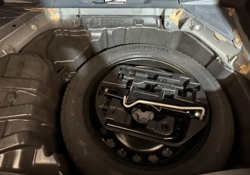 Vue rapprochée de la roue de secours et des outils dans le coffre d’une Renault Mégane gris foncé 2019.