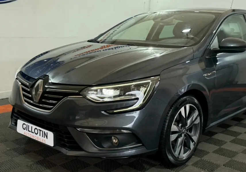 Renault Mégane Intens gris foncé vue 3/4 avant droit, phares LED et jantes alliage distinctives visibles.