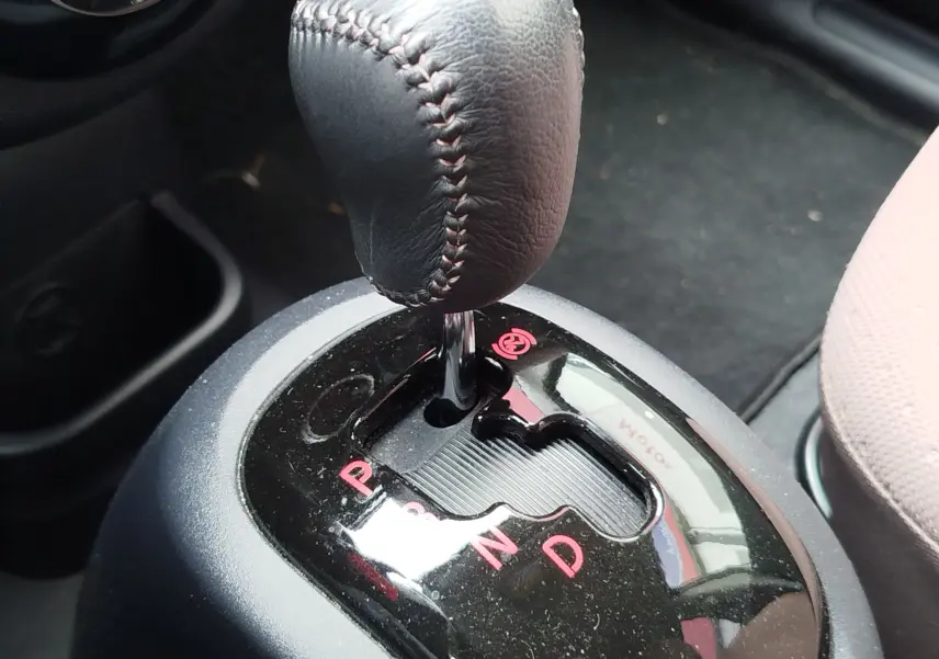 Gros plan sur le levier de vitesses automatique noir avec coutures visibles dans une Citroën C-ZERO blanche, version Confort.