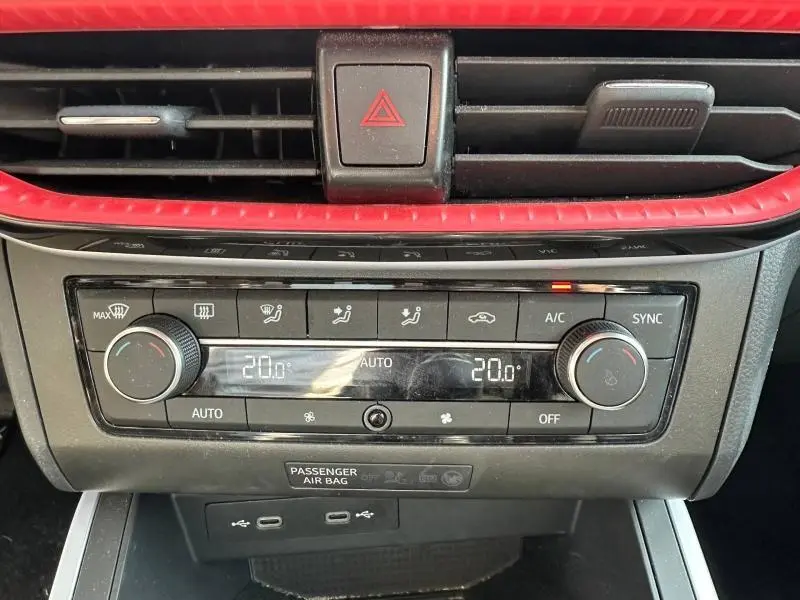 Gros plan sur la console centrale du SEAT Arona 2025, avec commandes climatisation et détail de la finition intérieure rouge.