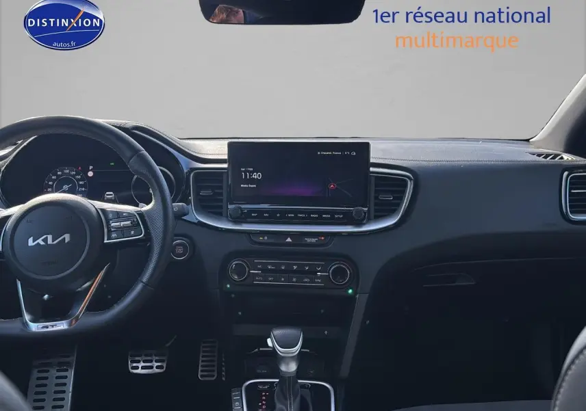 Vue intérieure avant du tableau de bord noir du KIA Xceed gris 2024 avec écran tactile et volant multifonction.