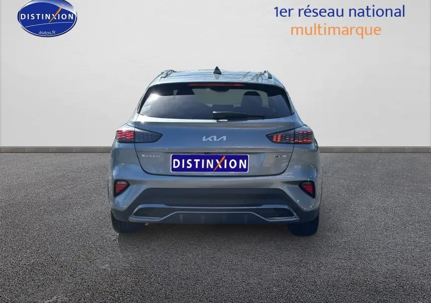 Vue arrière d'un KIA Xceed gris 2024 avec feux LED et becquet arrière, stationné sur sol goudronné.