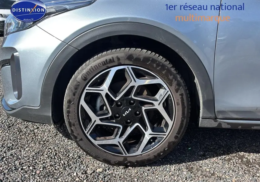Gros plan sur la roue avant gauche avec jante alu noire et argentée du KIA Xceed gris 2024.