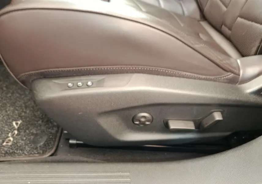 Gros plan sur les commandes de réglage électrique du siège avant droit en cuir marron du DS4 E-TENSE 225 gris clair.
