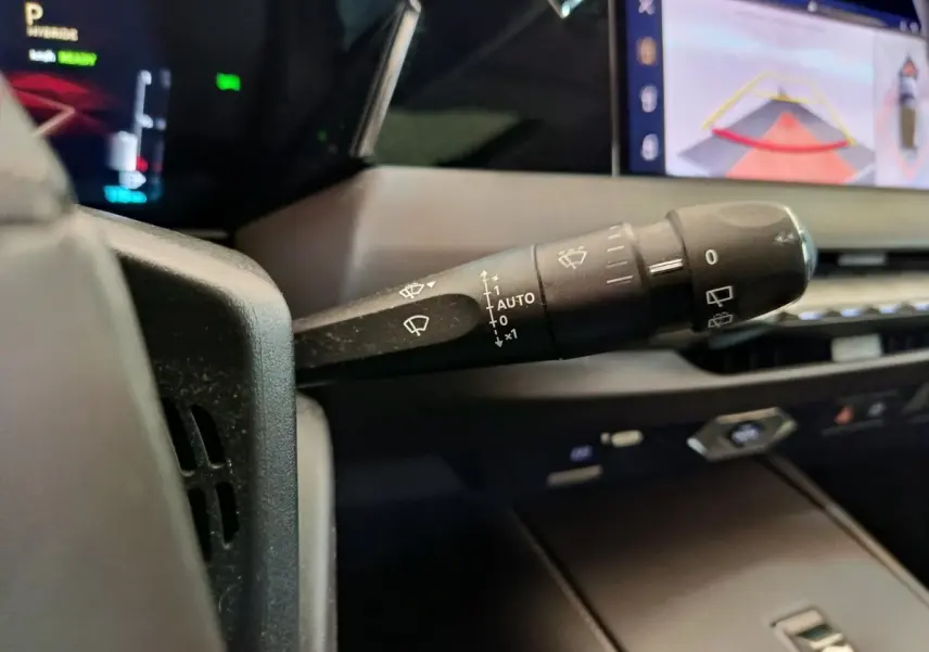 Gros plan sur la manette des essuie-glaces dans l’habitacle d’une DS4 E-TENSE 225 gris clair, avec écran tactile en arrière-plan.