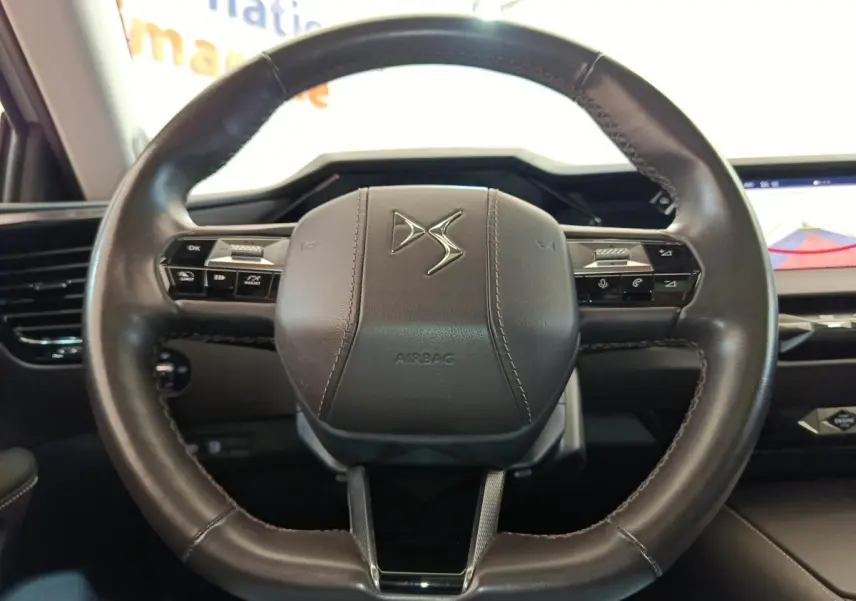 Vue rapprochée du volant cuir noir de la DS4 E-TENSE 225 avec commandes intégrées et tableau de bord numérique.