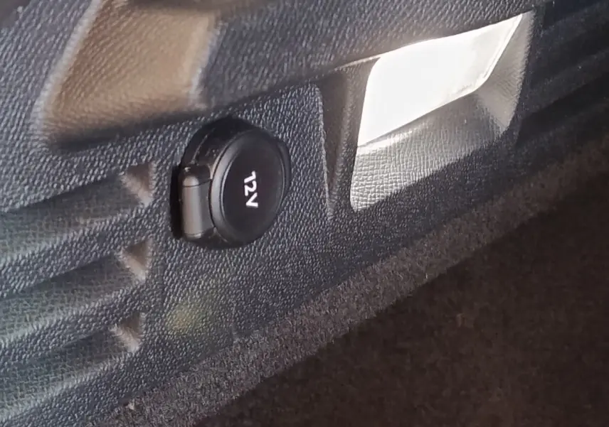 Prise 12V noire dans le coffre du DS4 E-TENSE 225 LA PREMIERE 2021, vue rapprochée sur revêtement noir.