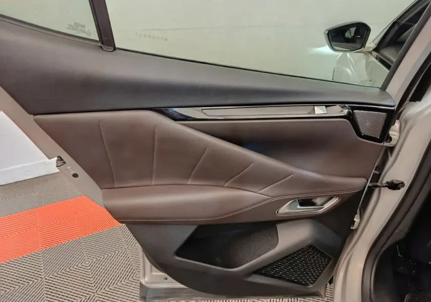 Vue intérieure côté gauche de la porte avant gris clair du DS4 E-TENSE 225 LA PREMIERE avec garniture cuir marron et insert noir brillant.