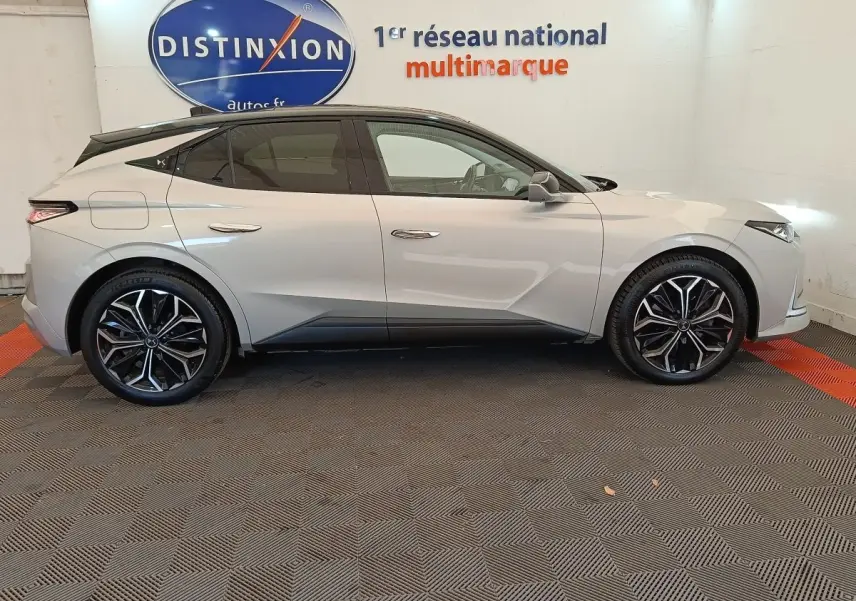Vue de profil côté gauche d'une DS4 E-TENSE 225 gris clair avec toit noir et jantes alliage distinctives en concession.