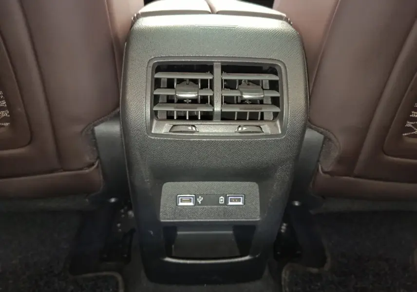 Vue rapprochée de la console arrière noire avec bouches d’aération et ports USB dans l’habitacle du DS4 E-TENSE gris clair.