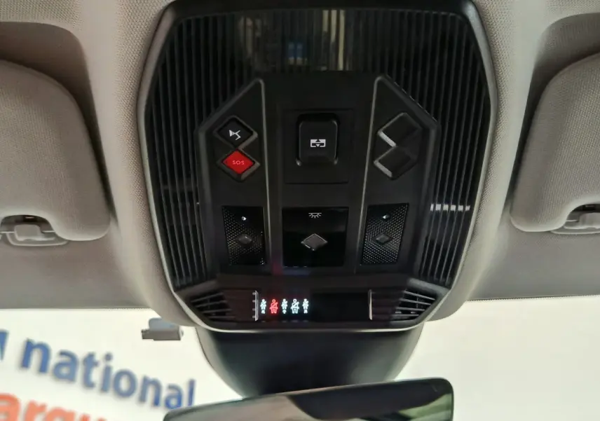 Vue intérieure en gros plan du panneau de commandes au plafond du DS4 E-TENSE gris clair, avec bouton SOS rouge visible.