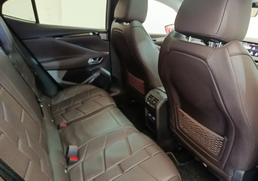 Vue intérieure arrière côté gauche du DS4 E-TENSE 225 gris clair, sièges en cuir marron avec console centrale et aérateurs.