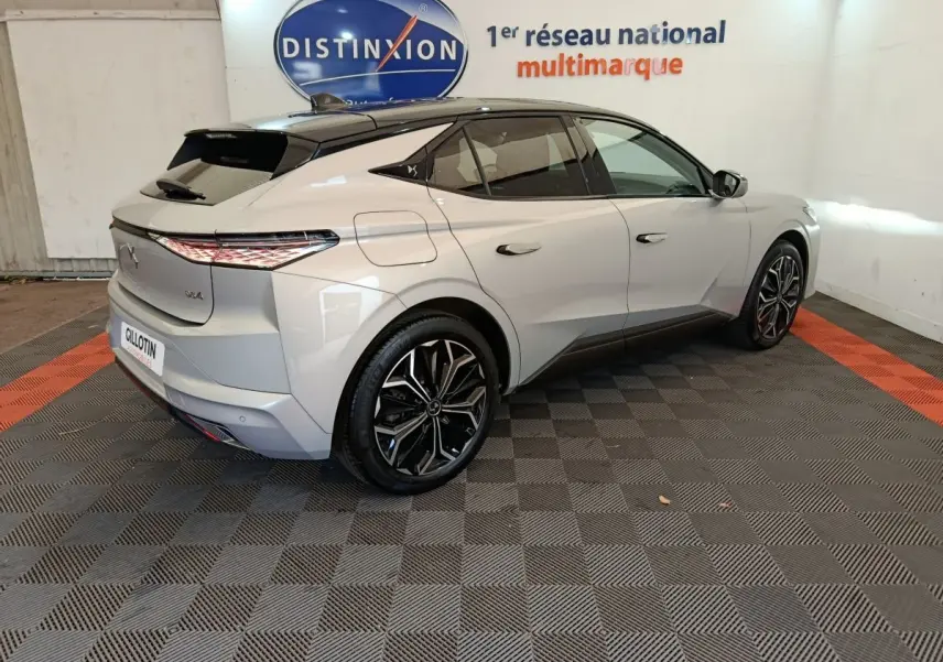 Vue 3/4 arrière droite d'une DS4 E-TENSE 225 gris clair avec feux LED et jantes alliage noires en showroom.